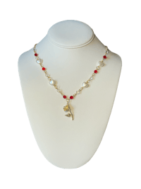 a necklace with pearls and red beads on a mannequin