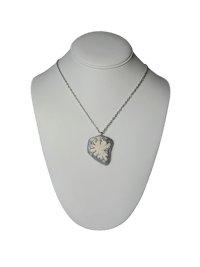 a necklace with a white and silver pendant on a mannequin